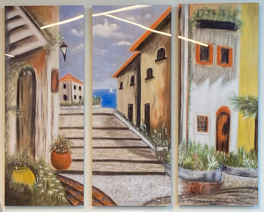 A limited edition acrylic gloss triptych print featuring a painting of an Italian street scene with cobblestone pathways, buildings, and a blue sky. Triptych.